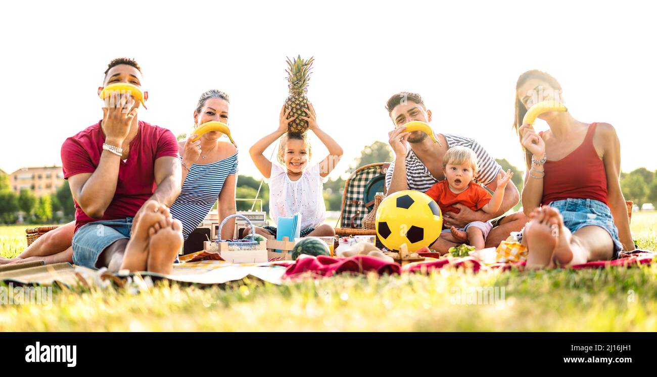 Young multicultural families having fun together with kids at pic nic party - Multiracial joy life style and love concept with happy people Stock Photo