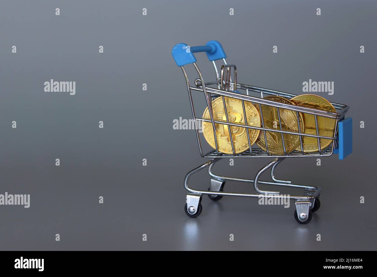 Shopping trolley and cryptocurrency. Bitcoin, Dogecoin and Ethereum. Grey background. Copy space Stock Photo