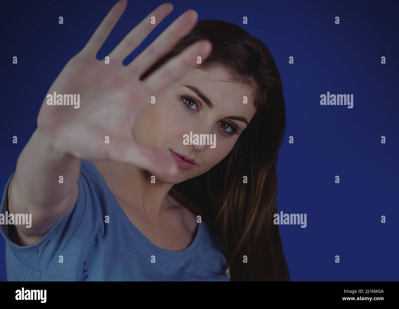 Portrait of caucasian woman gesturing stop sign against copy space on blue background Stock Photo