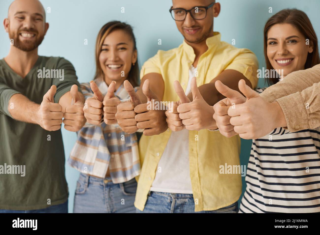 Diverse group of happy young men and women smiling and giving thumbs up together Stock Photo