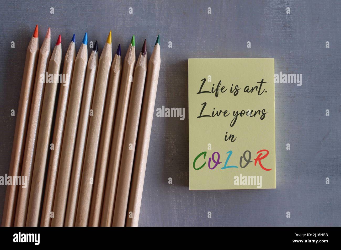 Color pencils and yellow notepaper with quotes LIFE IS ART. LIVE YOURS IN COLOR. Motivational quotes Stock Photo