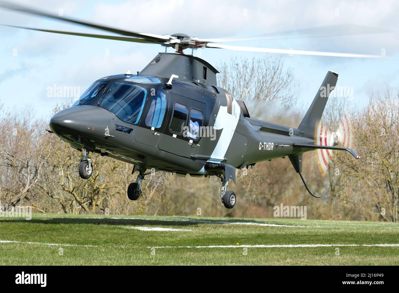 Agusta AW109 Grand New executive helicopter on approach to land at a racecourse helipad Stock Photo