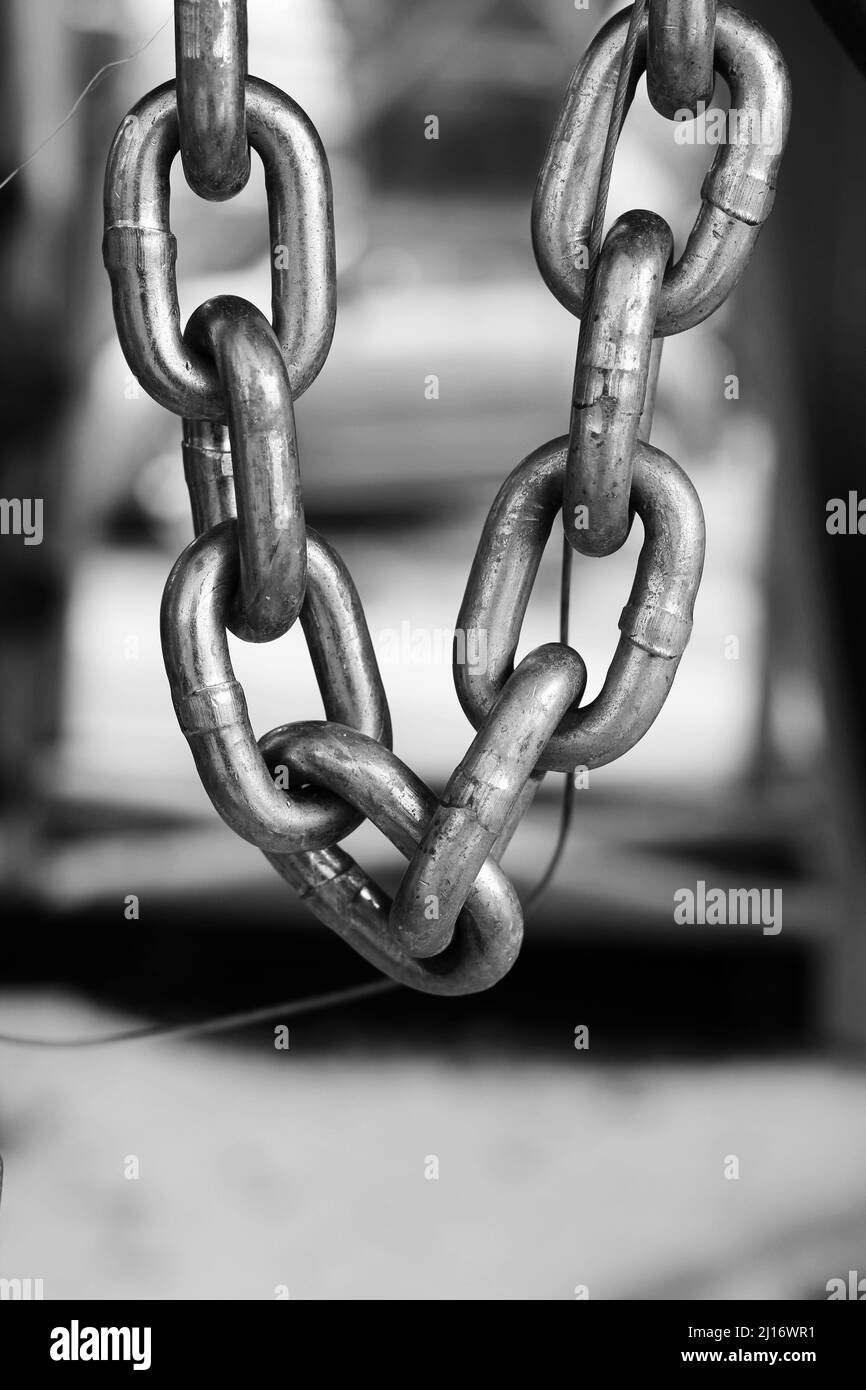 Closeup of a heavy chain with industrial metal links hanging down in