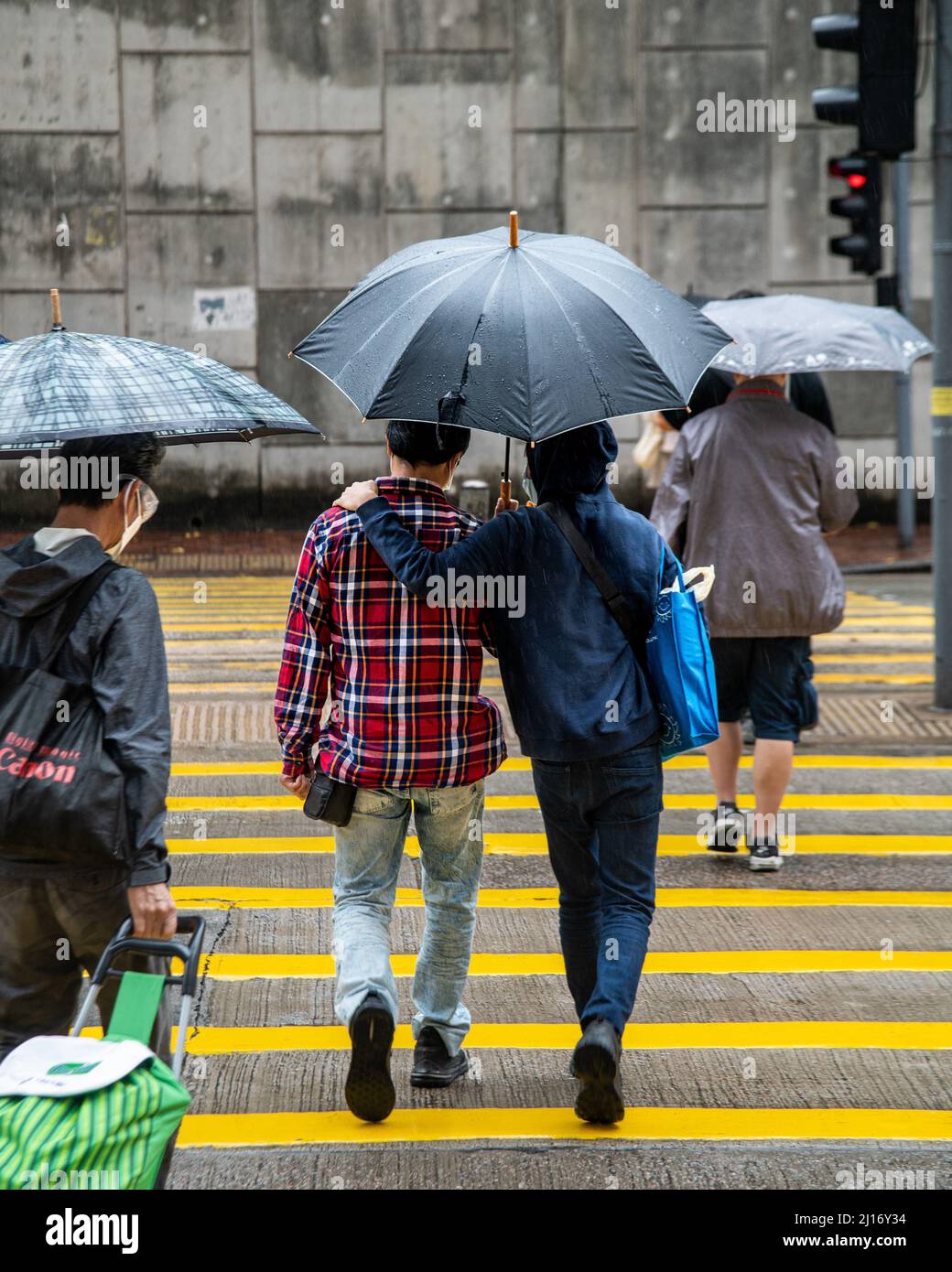 Hong Kong, Hong Kong. 23rd Mar, 2022. Two people share an umbrella to protect themselves from the rain as a northern monsoon brings cooler weather and rain to Hong Kong. A rainy, spring day in Hong Kong. (Photo by Ben Marans/SOPA Images/Sipa USA) Credit: Sipa USA/Alamy Live News Stock Photo