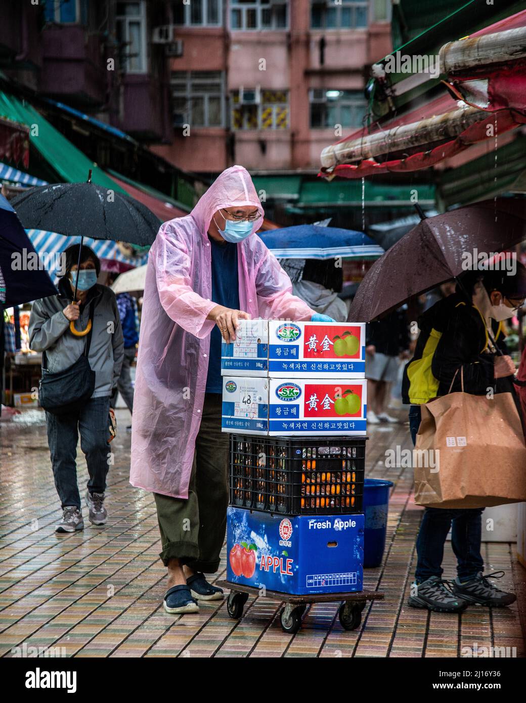 Hong Kong, Hong Kong. 23rd Mar, 2022. A worker wearing a raincoat loads fruit as a northern monsoon brings cooler weather and rain to Hong Kong. A rainy, spring day in Hong Kong. (Photo by Ben Marans/SOPA Images/Sipa USA) Credit: Sipa USA/Alamy Live News Stock Photo