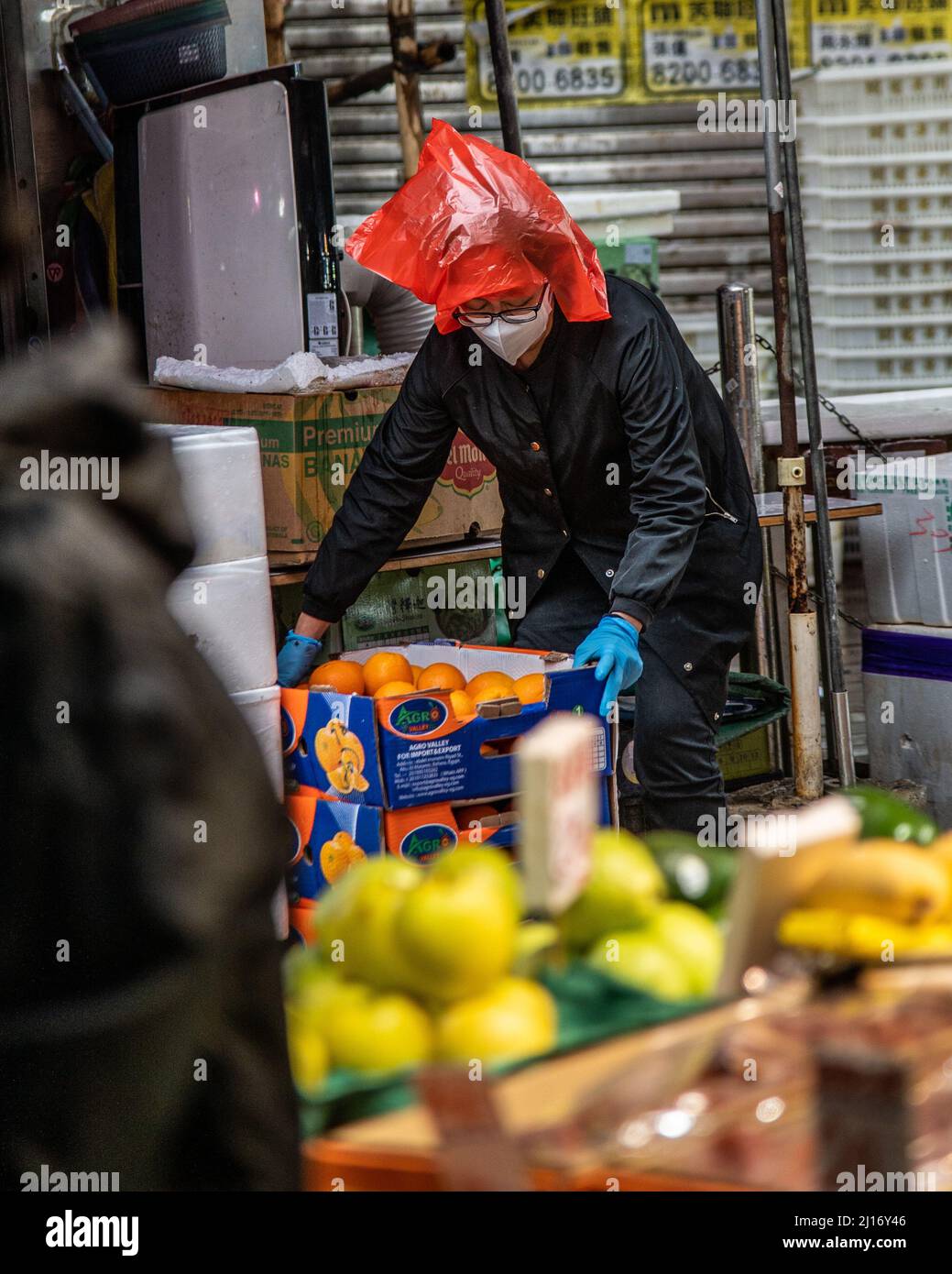 A worker wearing a plastic bag for a hat to protect him from the rain,  loads fruits as a northern monsoon brings cooler weather and rain to Hong  Kong. A rainy, spring