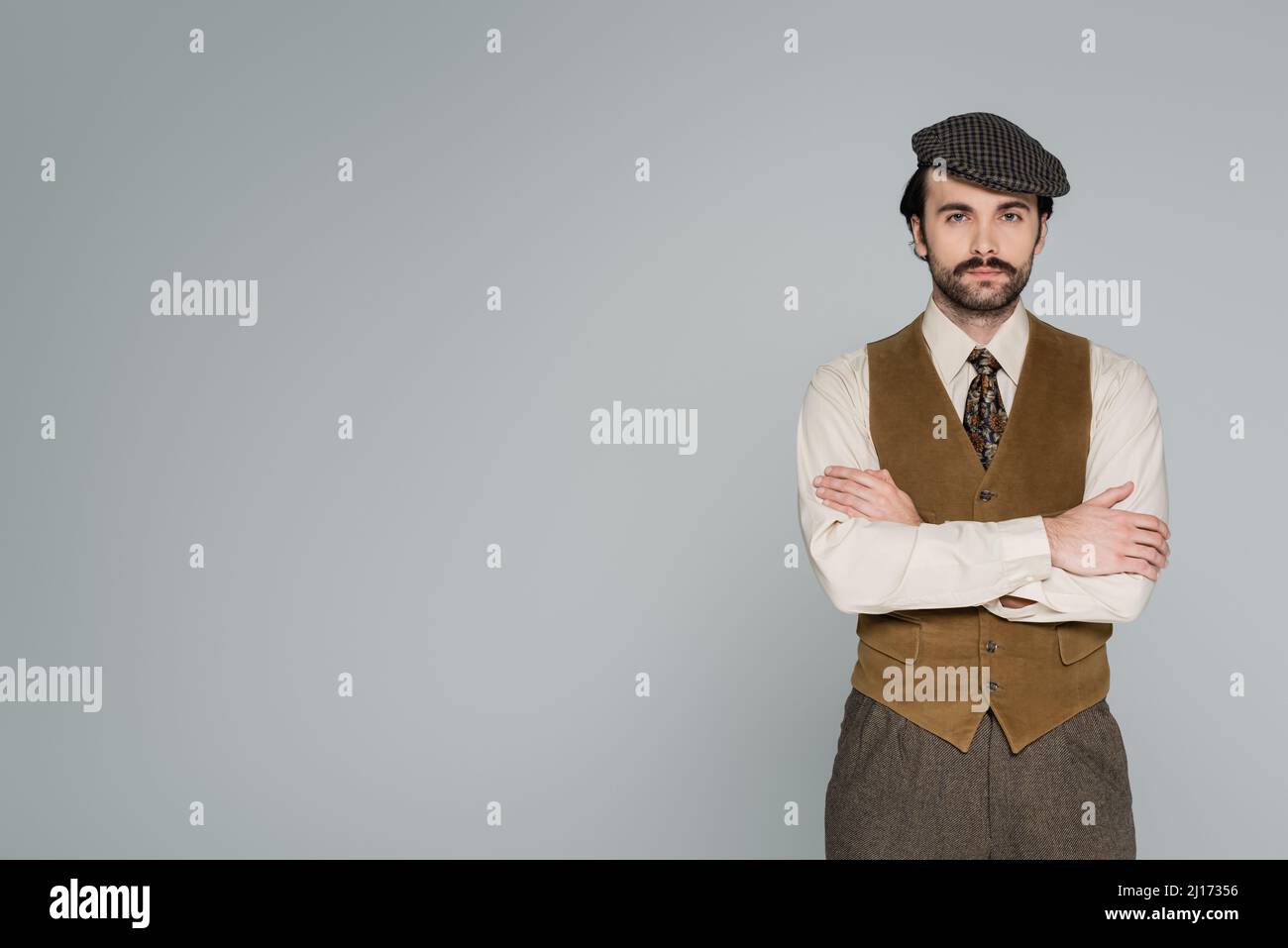man with mustache and retro clothing standing with crossed arms ...