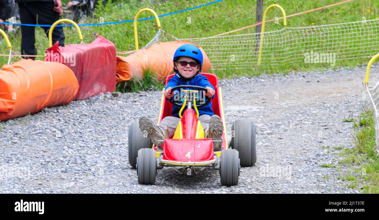 young boy rolling down hill in a go kart in the french alps at super devoluy ,holiday activity ,ski resort in summer . Stock Photo