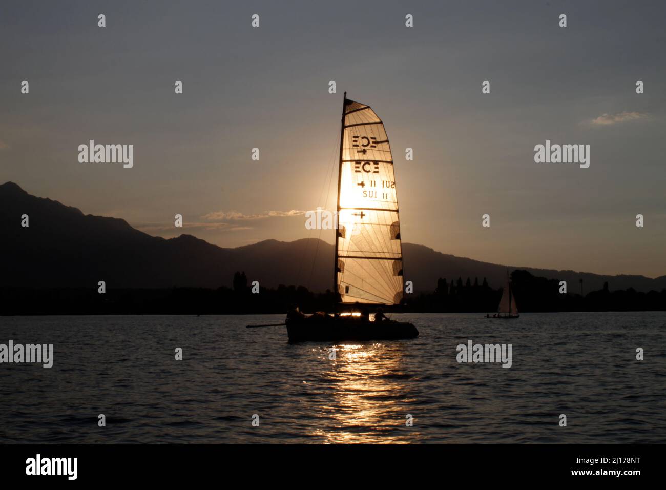 Sun behind a sailing boat on the Lake Thun in Switzerland Stock Photo