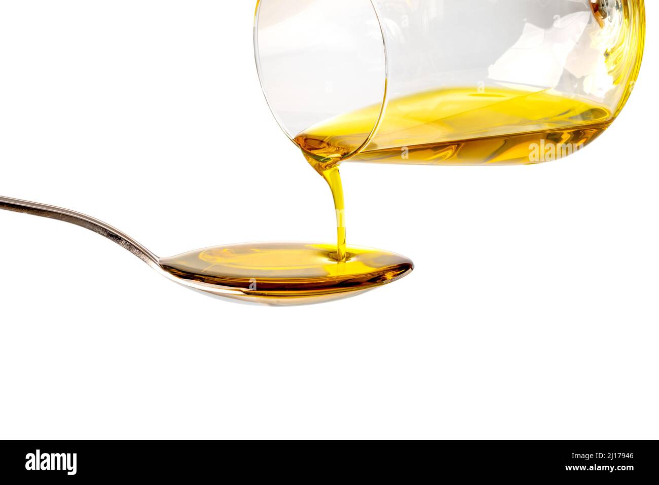 Extra virgin oil poured from glass into spoon, isolated on white background, clipping path Stock Photo