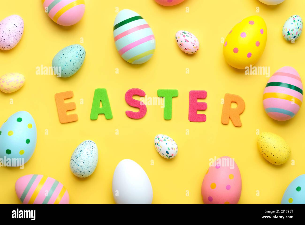 Happy Easter. Easter composition with colored letters and colored easter painted eggs over yellow background Stock Photo