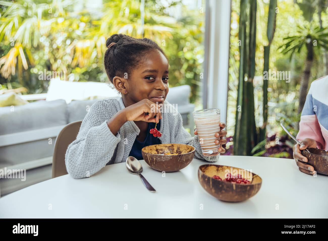 Smiling girl having berries at table in dining room Stock Photo - Alamy