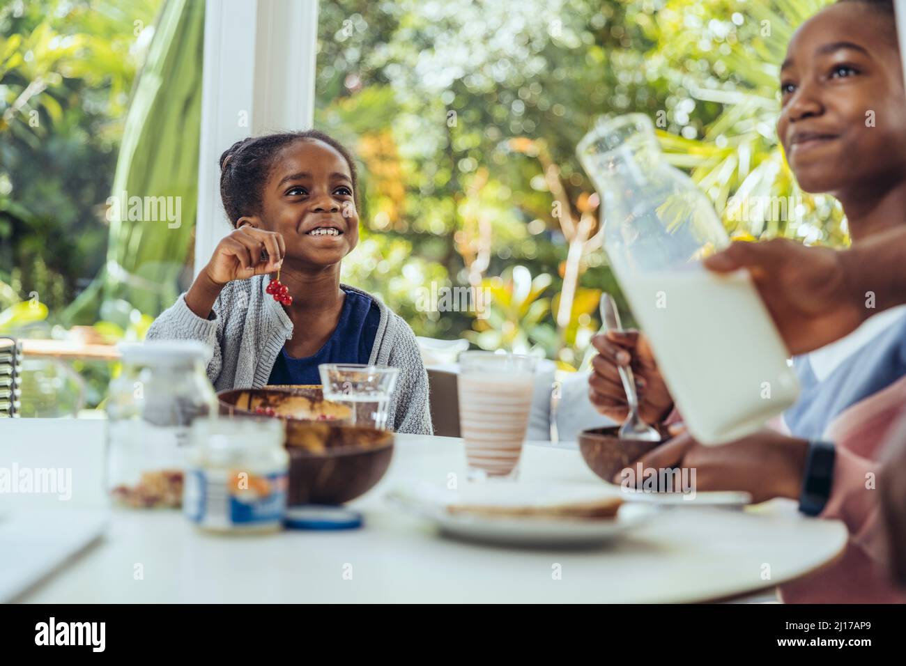 Smiling sisters having berries at breakfast table Stock Photo - Alamy