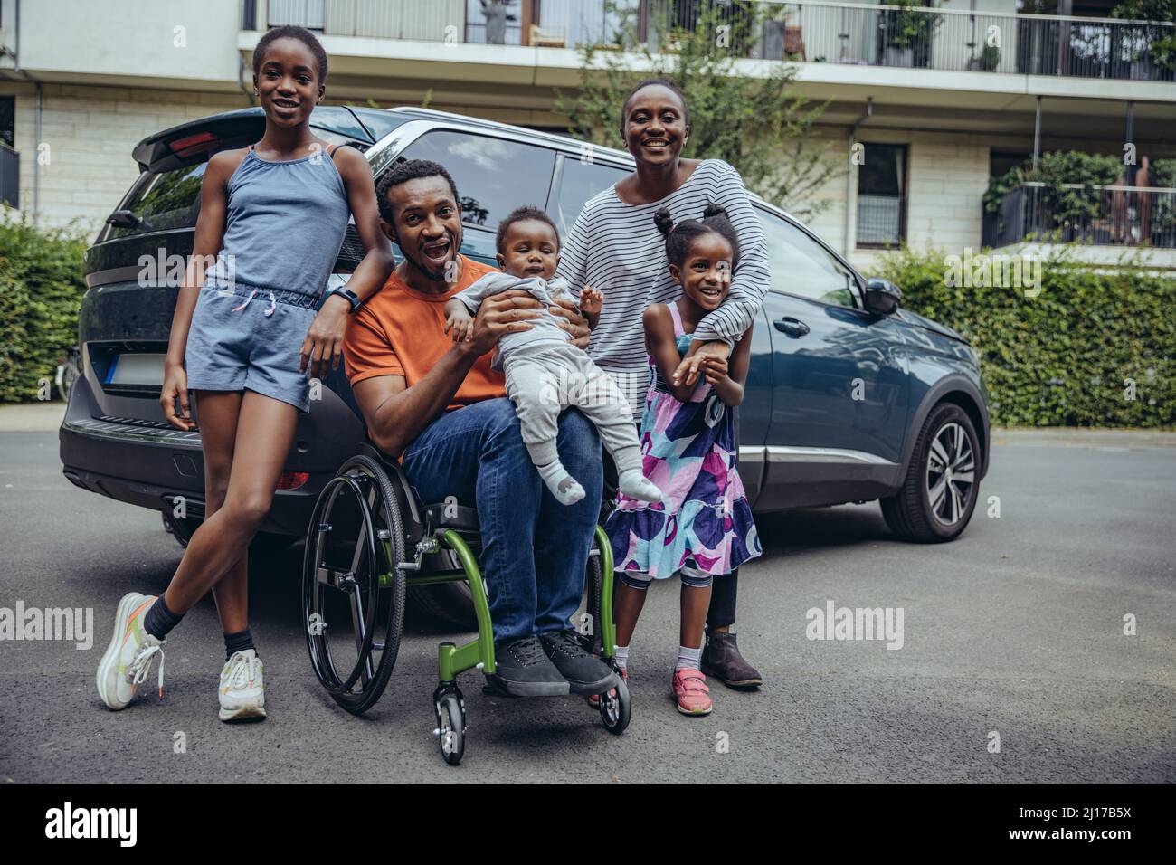 Cheerful disabled father with family at car Stock Photo