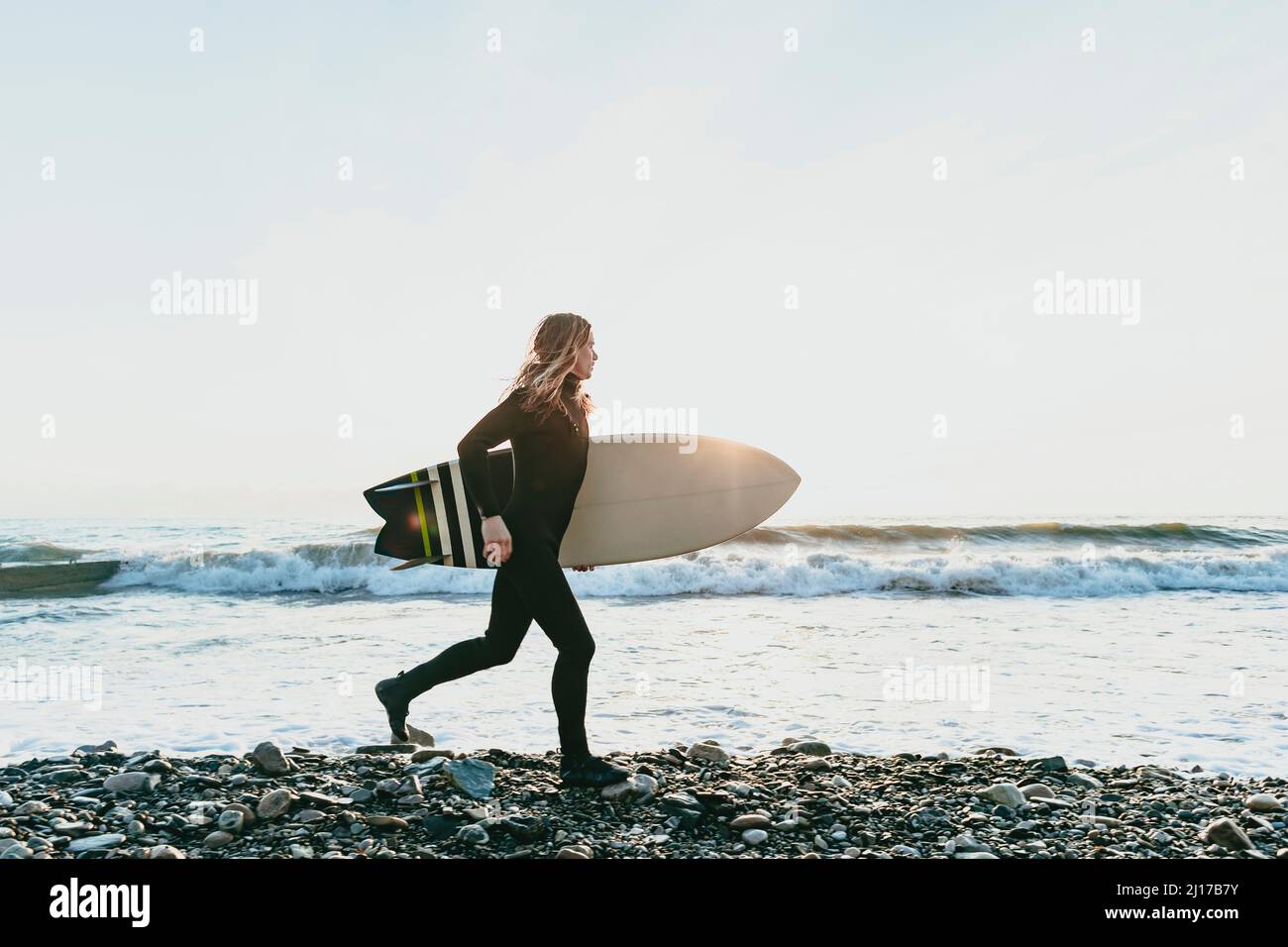 Man with surfboard running on beach Stock Photo