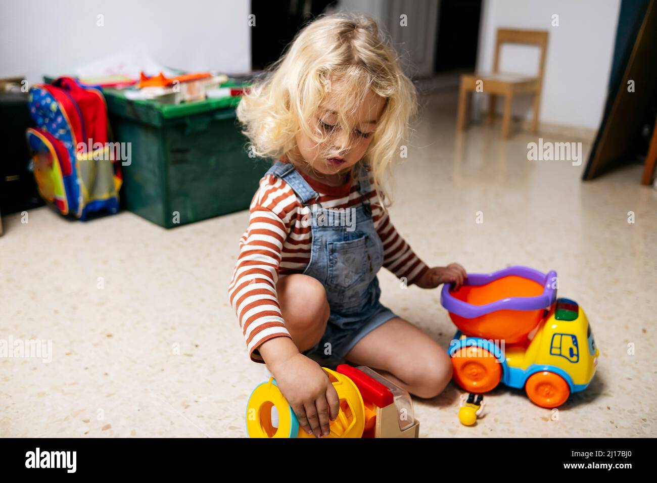 Blond boy playing with toy cars on floor at home Stock Photo