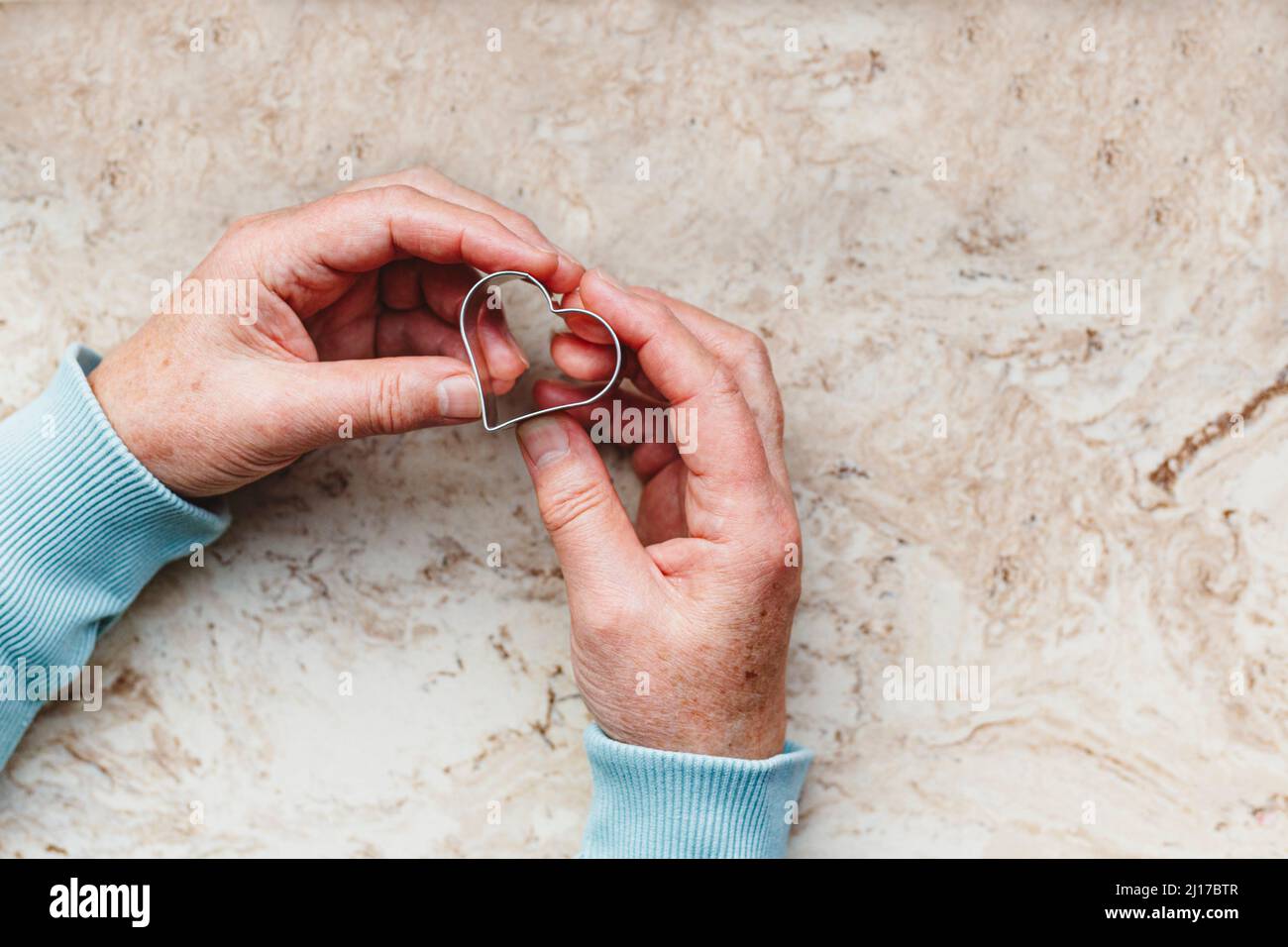 Senior woman holding heart shaped cookie cutter Stock Photo