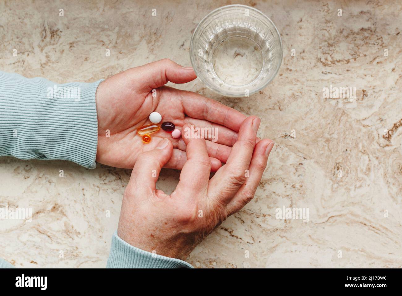 Senior woman taking medicinal pills with glass of water Stock Photo