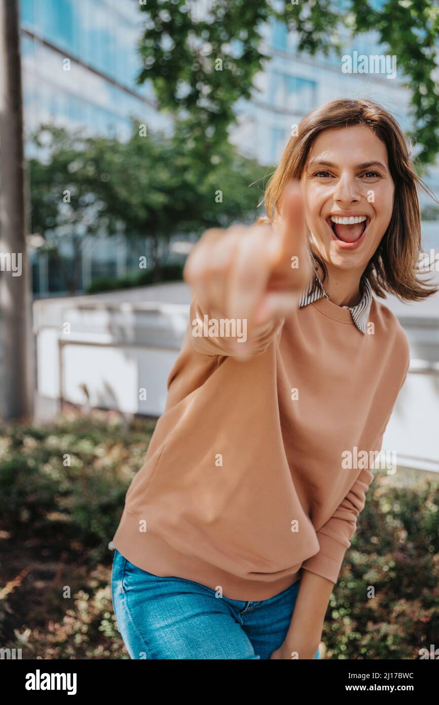 Cheerful woman pointing finger in office park Stock Photo