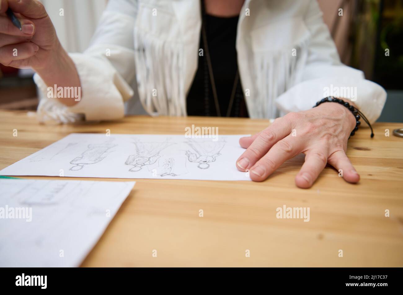 Focus on the hand of an unrecognizable fashion designer holding a ...