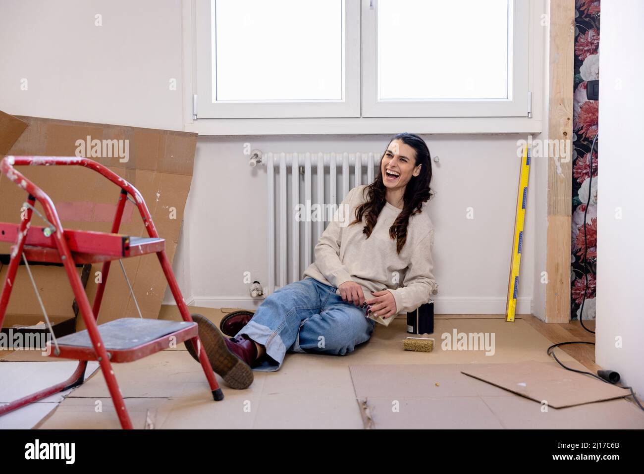 Happy woman sitting on ground at new home Stock Photo - Alamy