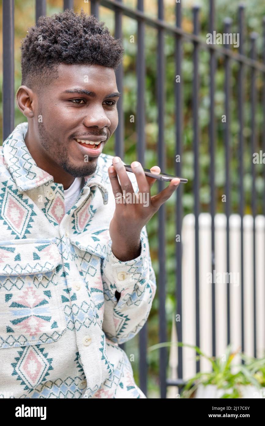 Smiling man talking on mobile phone through speaker Stock Photo