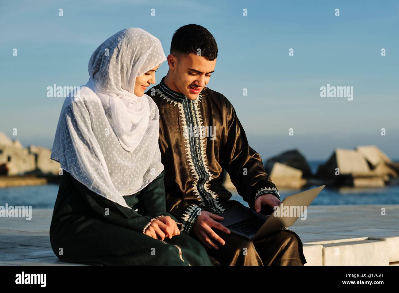Young woman sitting by man using laptop Stock Photo