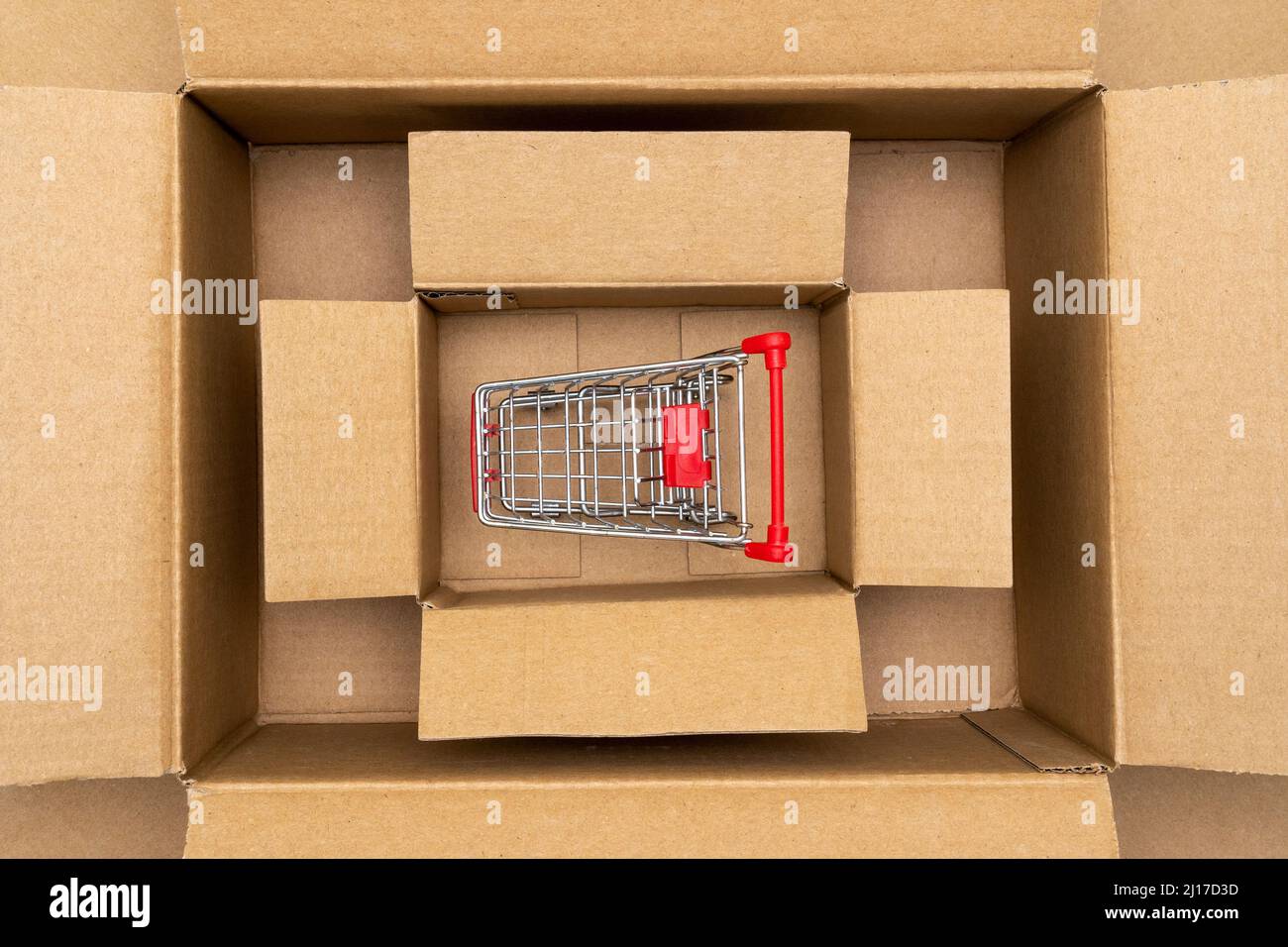 Shopping cart inside open rectangular cardboard box. Online internet shopping concept, e-commerce Stock Photo