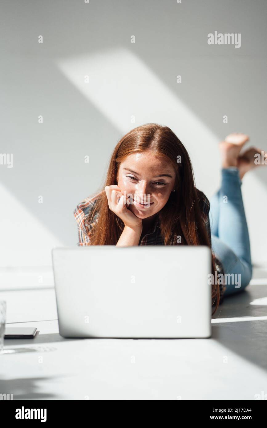 Smiling woman using laptop at home Stock Photo