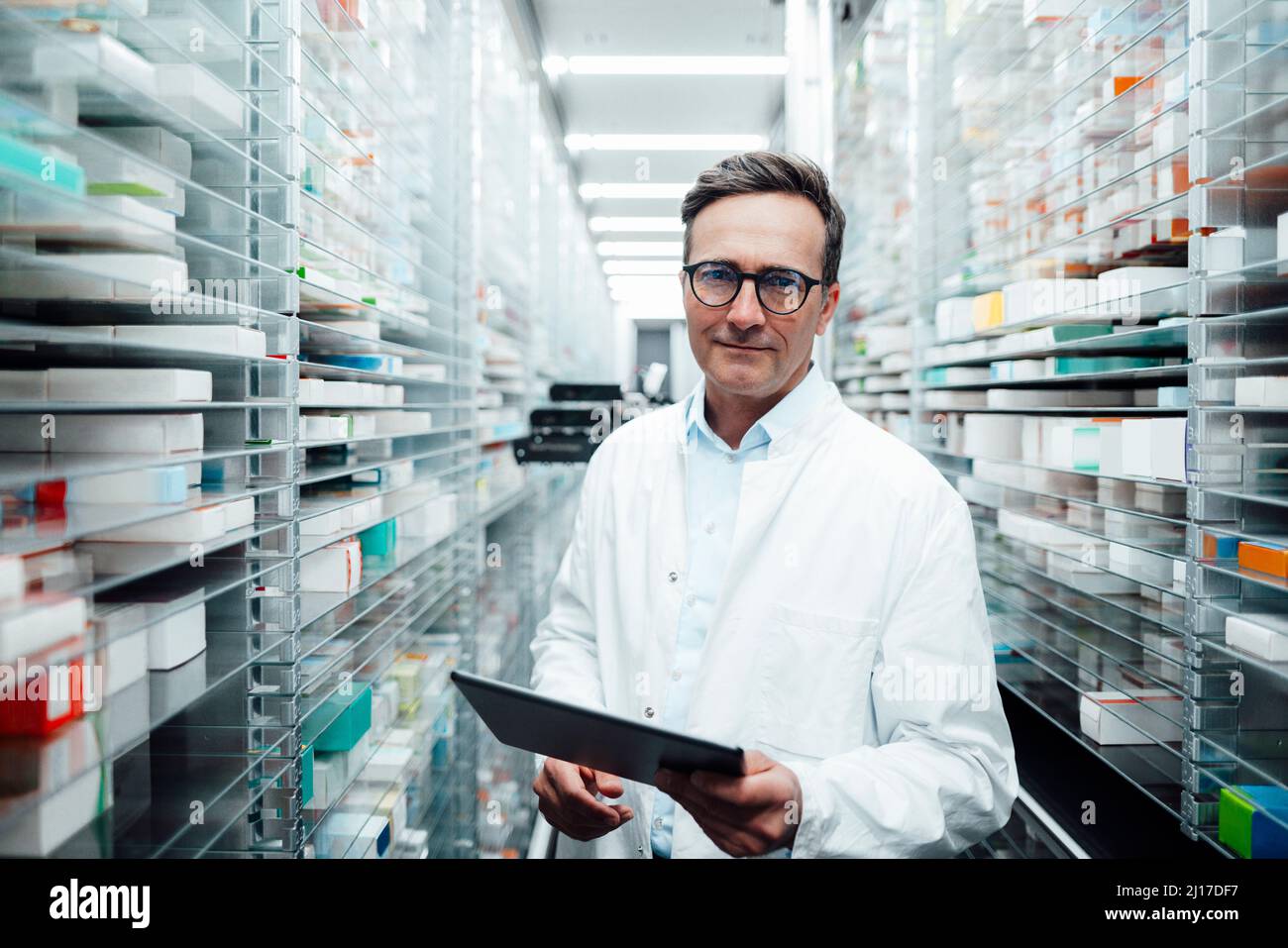 Pharmacist with tablet PC standing in storage room at pharmacy Stock Photo