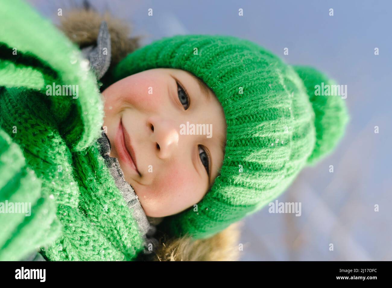 Smiling boy wearing green knit hat and scarf Stock Photo