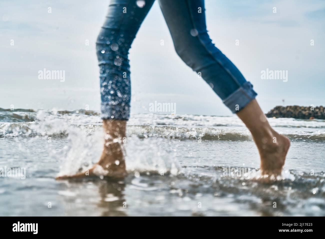 Woman running in water at beach Stock Photo