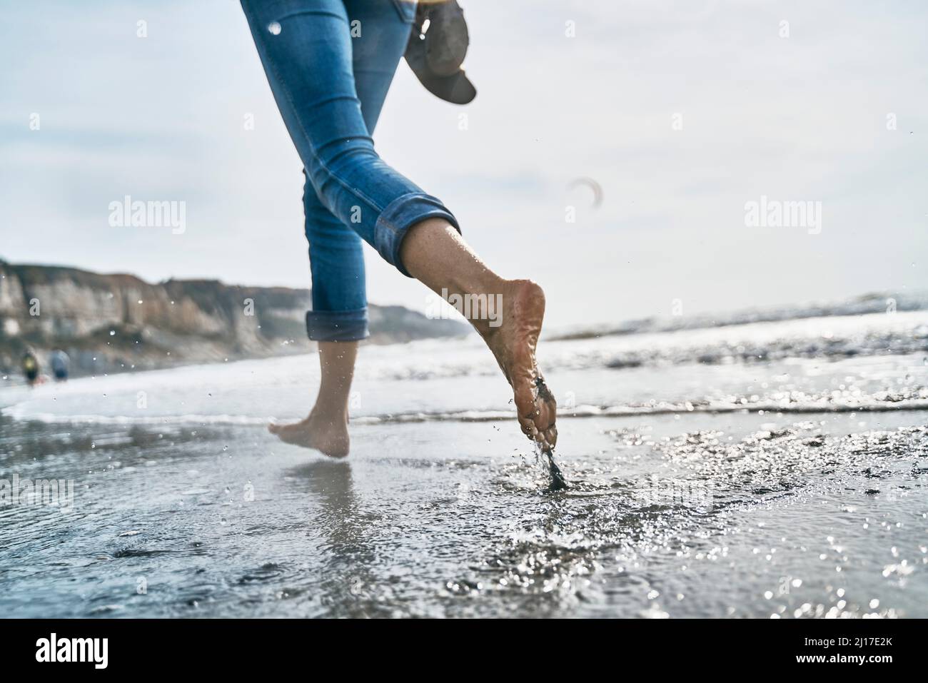 Woman running barefoot in sea at vacation Stock Photo