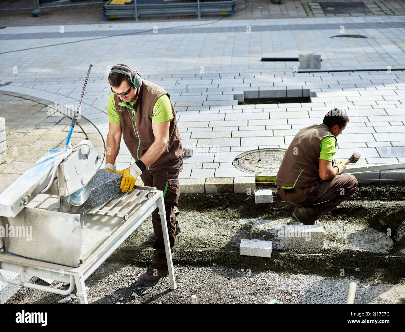 Paver cutting paving stone by coworker working in background Stock Photo Alamy