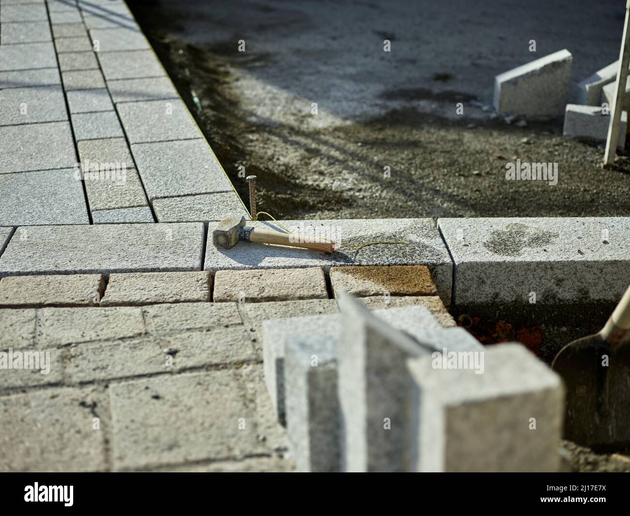 Hammer on paving stone at incomplete footpath Stock Photo