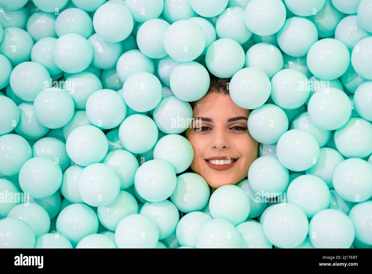 Smiling woman amidst blue balls Stock Photo - Alamy