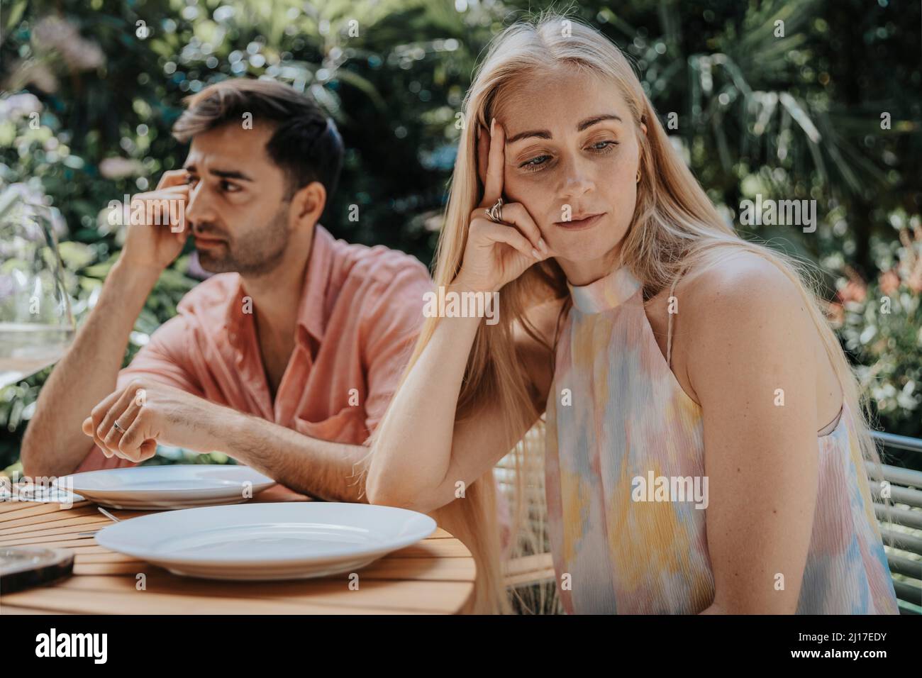 Couple ignoring each other at outdoor table Stock Photo