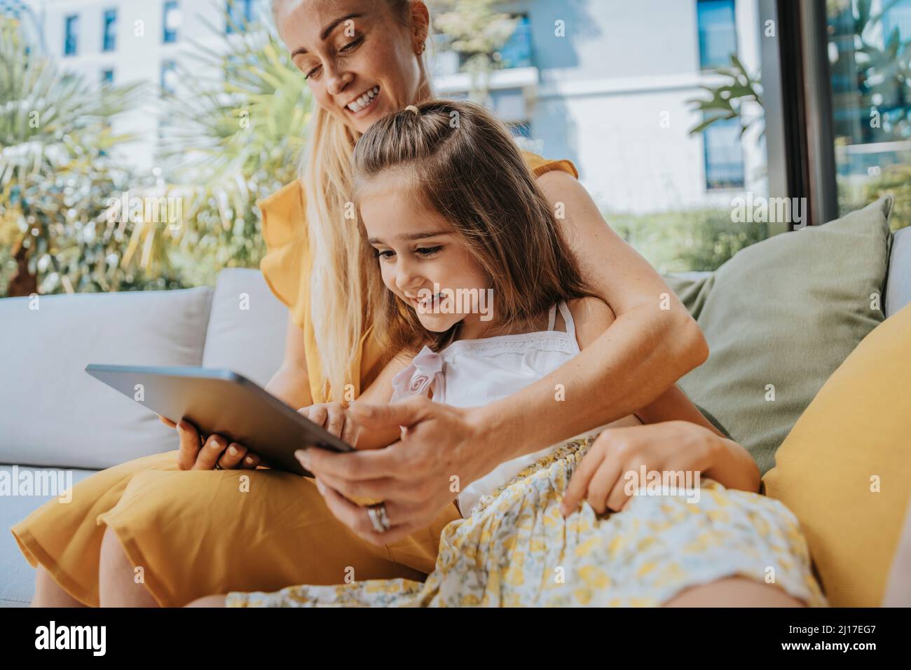 Happy mother and daughter using tablet computer in patio Stock Photo