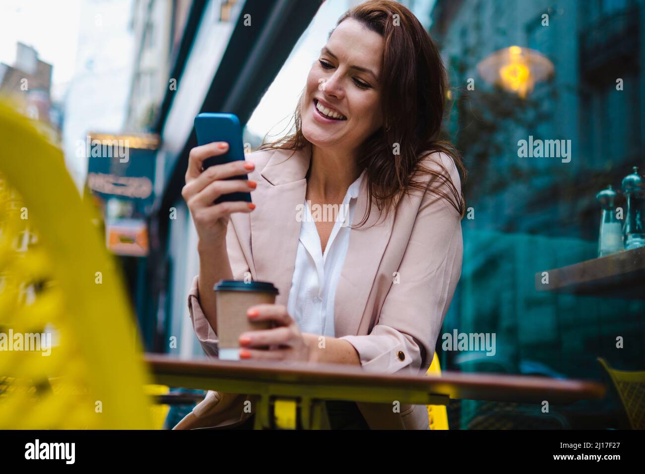 Happy woman using smart phone in sidewalk cafe Stock Photo