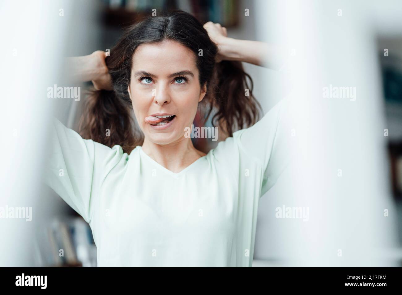 Woman holding hair and sticking out tongue in cafe Stock Photo Alamy