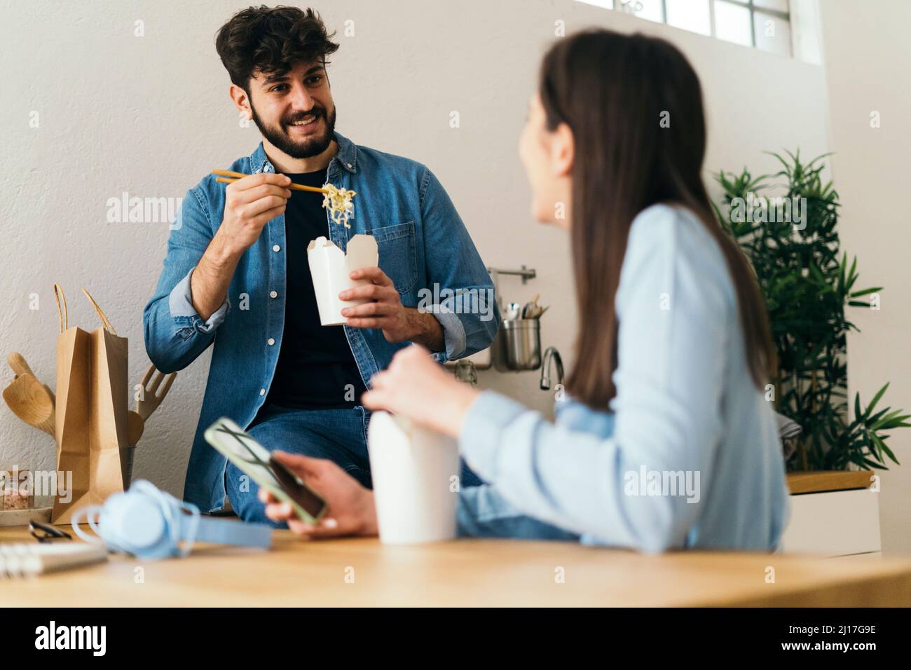 Man eating noodles spending leisure time with girlfriend at home Stock Photo