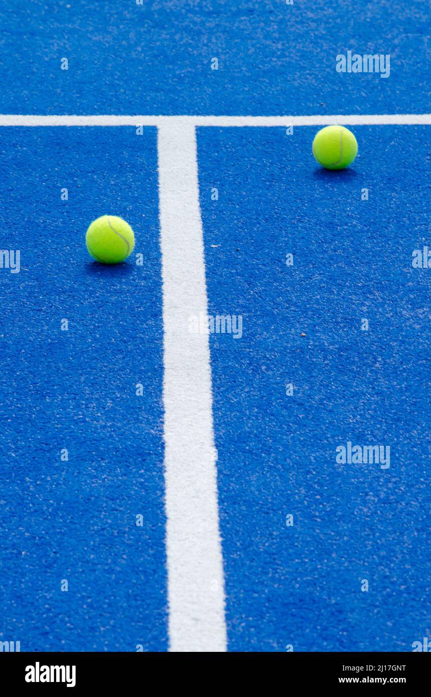 two balls and lines of a blue paddle tennis court, racket sports