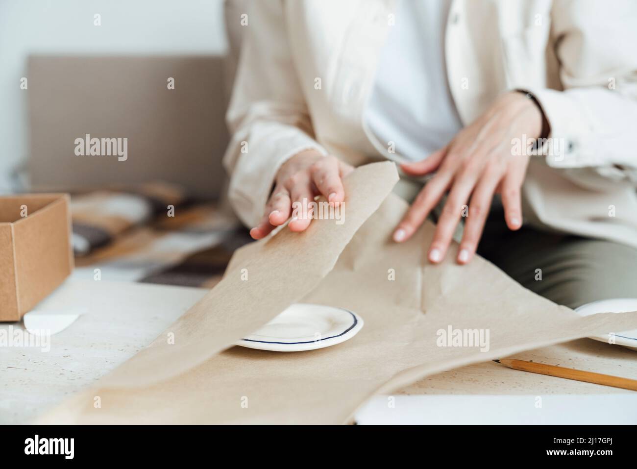 Craftswoman packing ceramic plate in wrapping paper for shipping Stock Photo