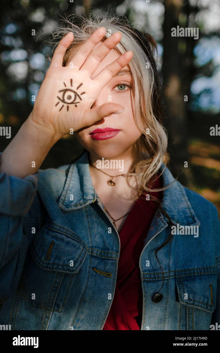 Young woman showing eye sign tattoo on her hand Stock Photo