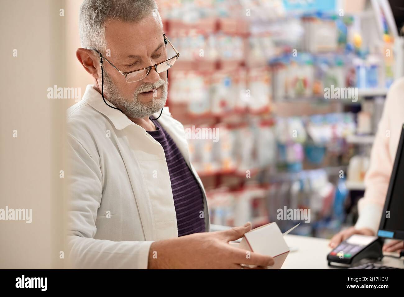 Pharmacist reading instructions on medicine box at pharmacy store Stock Photo