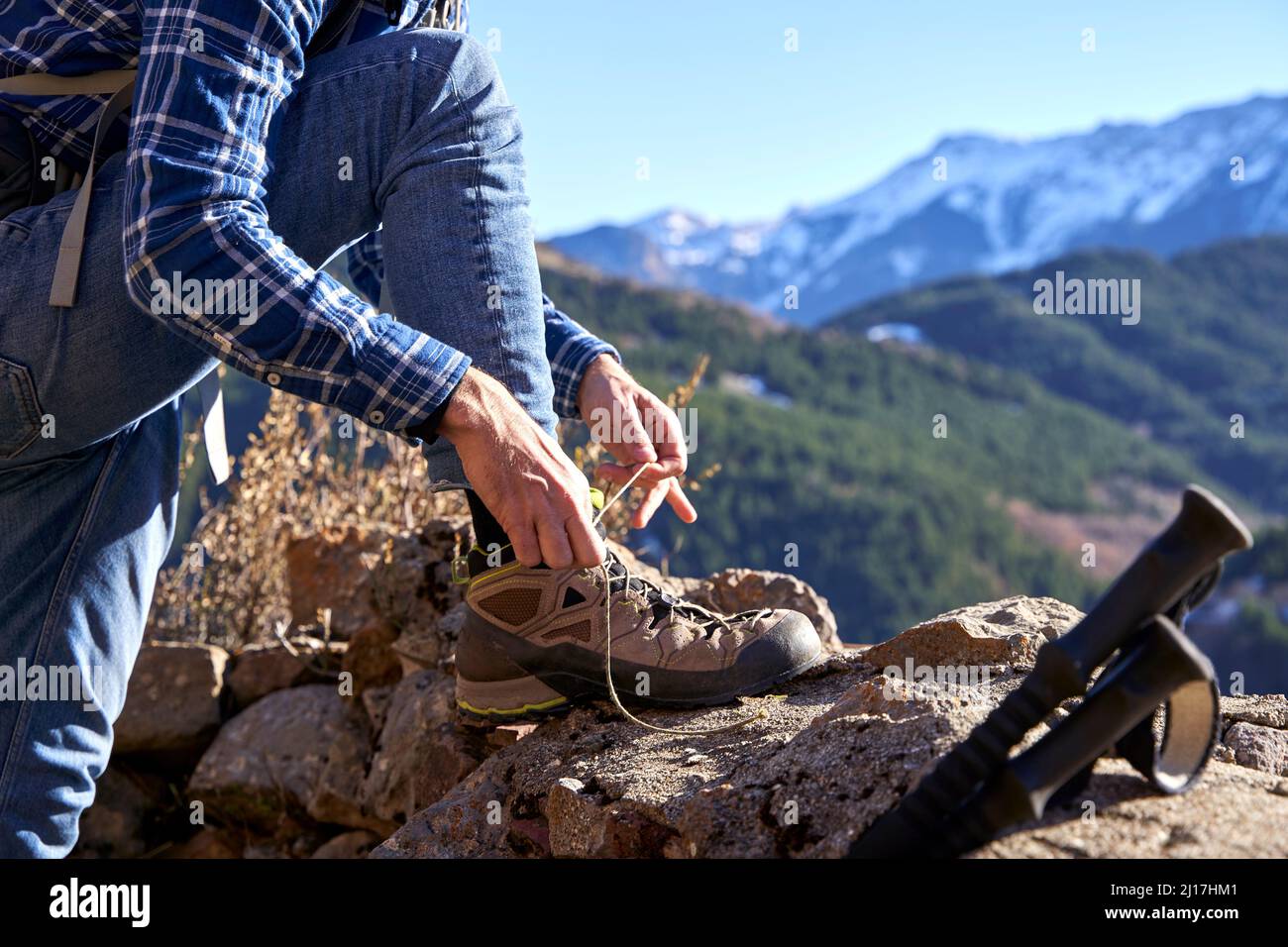 Hiker tying shoelace on sunny day Stock Photo