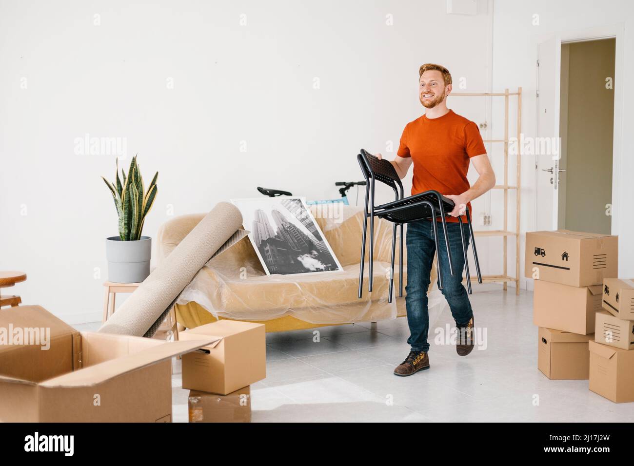 Young man holding chair walking in living room at home Stock Photo Alamy