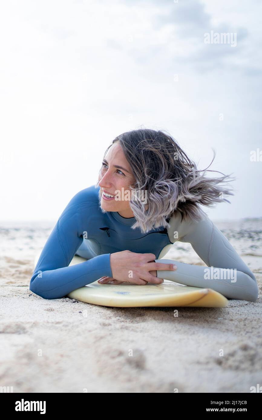 Smiling woman lying on surfboard hires stock photography and images