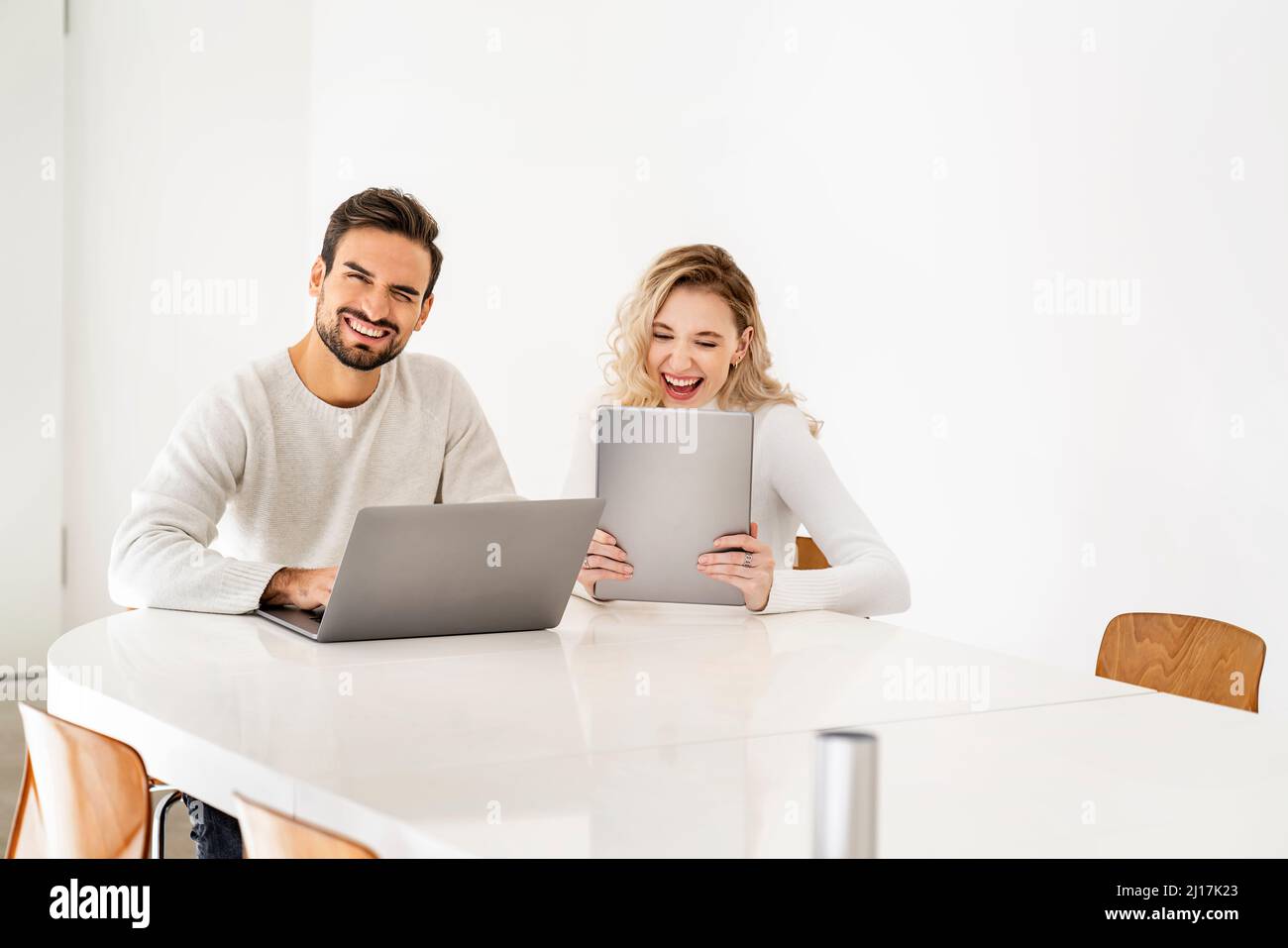 Cheerful young freelancers with wireless technologies sitting at table Stock Photo
