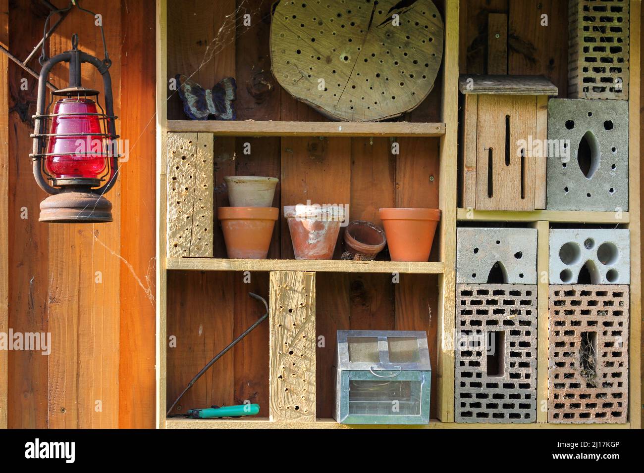 Shelf with insect hotel and garden utensils Stock Photo